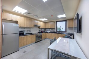 A modern kitchen with stainless steel appliances, wooden cabinets, and a large window. - Bloomfields 2BR plus Maid  Mina Al Fajer (Dibba)