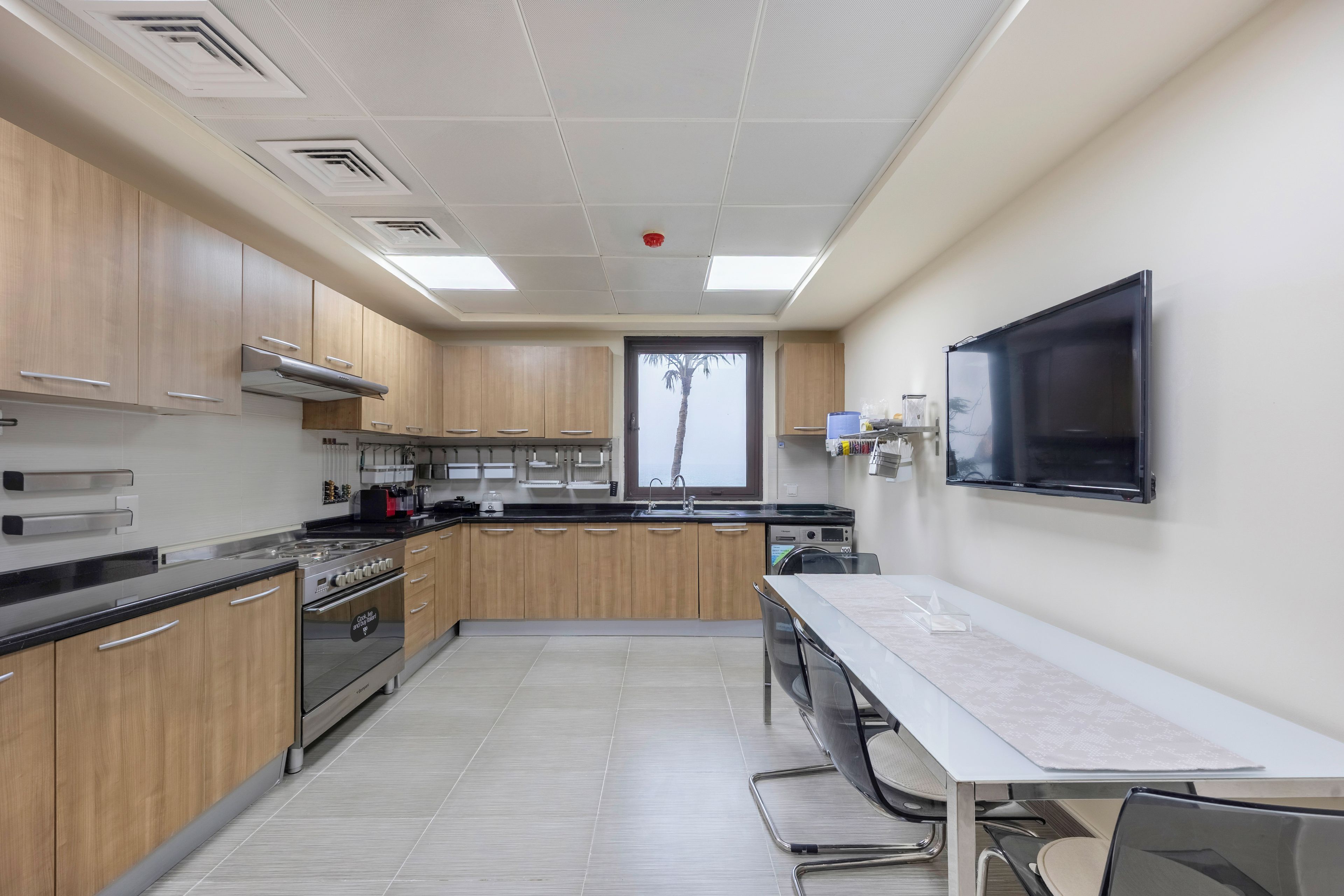 Une cuisine moderne avec des meubles en bois, une cuisinière en acier inoxydable et une grande fenêtre.