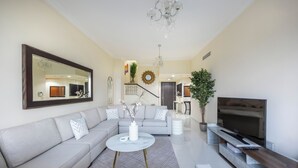 Ein modernes Wohnzimmer mit einem grauen Sofa, einem Couchtisch, einem Fernseher und einer Kristallleuchtre.