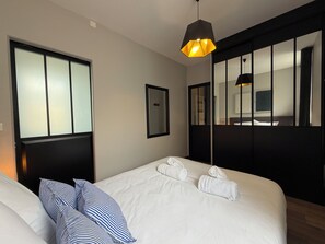 Een hotelkamer met een groot bed, een nachtkastje, een spiegel en een hanglamp.