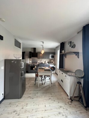 A modern kitchen with a dining area, a refrigerator, a microwave, and a sink. - Harbor Master's Office—stunning harbor view—downtown (Port-en-Bessin-Huppain)