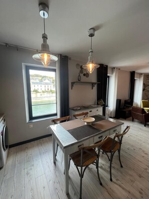 A modern kitchen with a dining table, chairs, and pendant lights. - Harbor Master's Office—Breathtaking Harbor View—Downtown (Port-en-Bessin-Huppain)