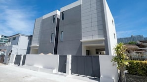 Un edificio moderno de dos pisos con techo plano, ventanas grandes y entrada protegida por una reja.