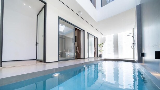 Una piscina interior con paredes de vidrio transparente, diseño moderno y estética minimalista.