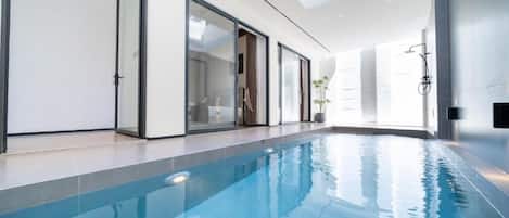 Una piscina interior con paredes de vidrio transparente, diseño moderno y estética minimalista.