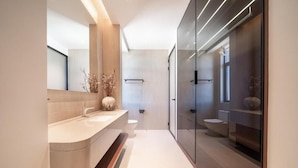 Un baño moderno con un tocador curvo, cabina de ducha de vidrio y diseño minimalista.