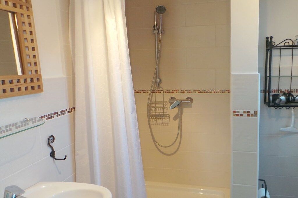 Een badkamer met een douche, een wastafel en een spiegel.
