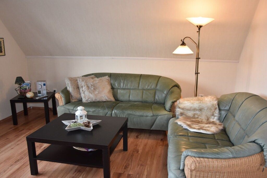 Un salon avec un canapé vert, une table basse noire et un lampadaire.