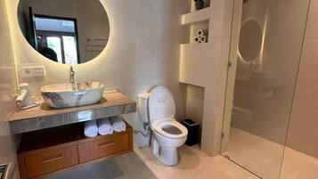 A modern bathroom with a round mirror, a toilet, and a glass shower enclosure.