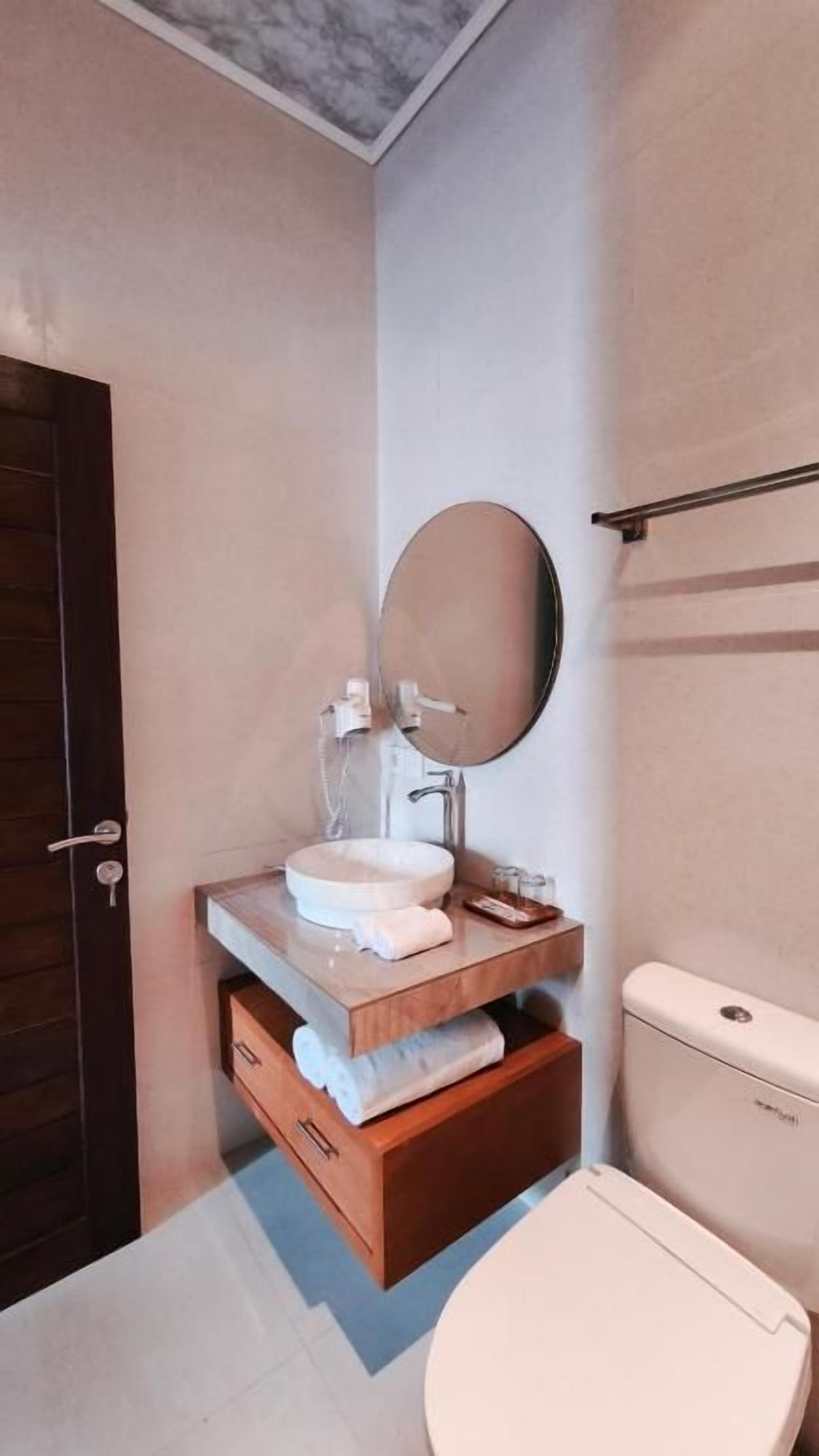 A bathroom with a toilet, a sink with a mirror, and a towel rack.