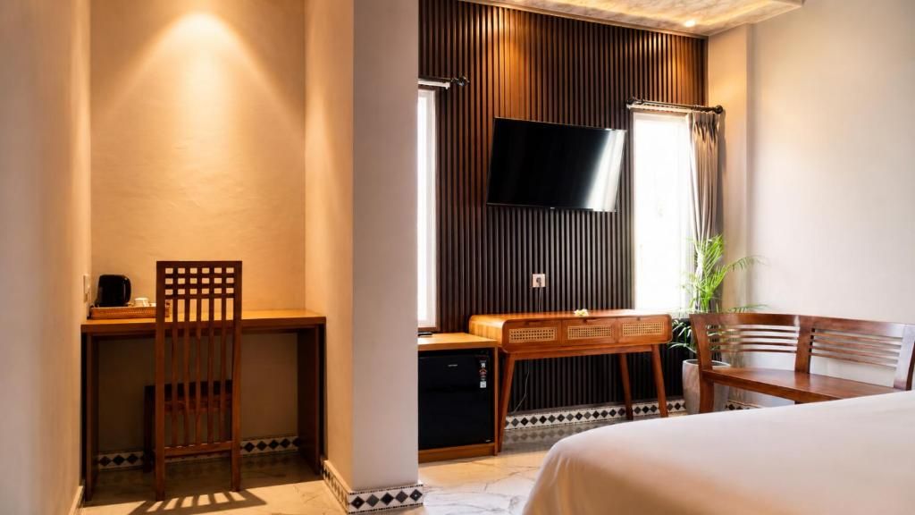 A hotel room with a bed, a desk, a chair, a television, and a window with curtains.