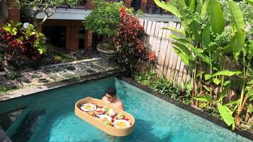 A person in a pool with a floating tray of food.