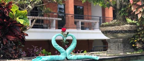 A swimming pool with a decorative swan made of towels and a rose.
