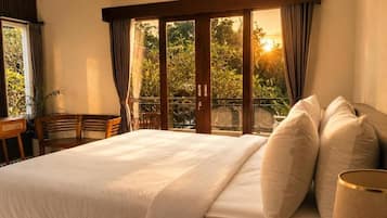 Camera d'albergo con un letto grande, una scrivania e vista sul verde dalla finestra.