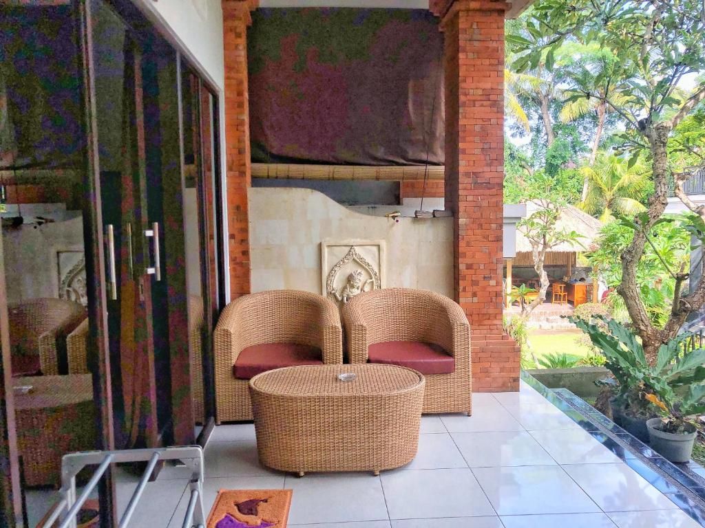 Una habitación con mobiliario de mimbre, suelo de baldosas y vistas a un jardín.