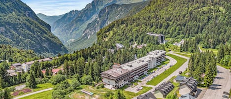 A hotel with multiple floors, surrounded by lush greenery and mountains.