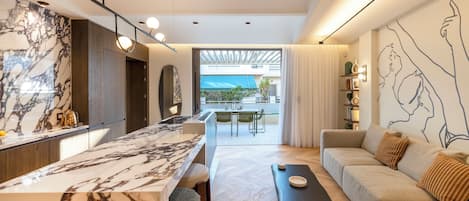 A modern kitchen with a marble countertop, a dining area with a table and chairs, and a living area with a sofa and a coffee table.
