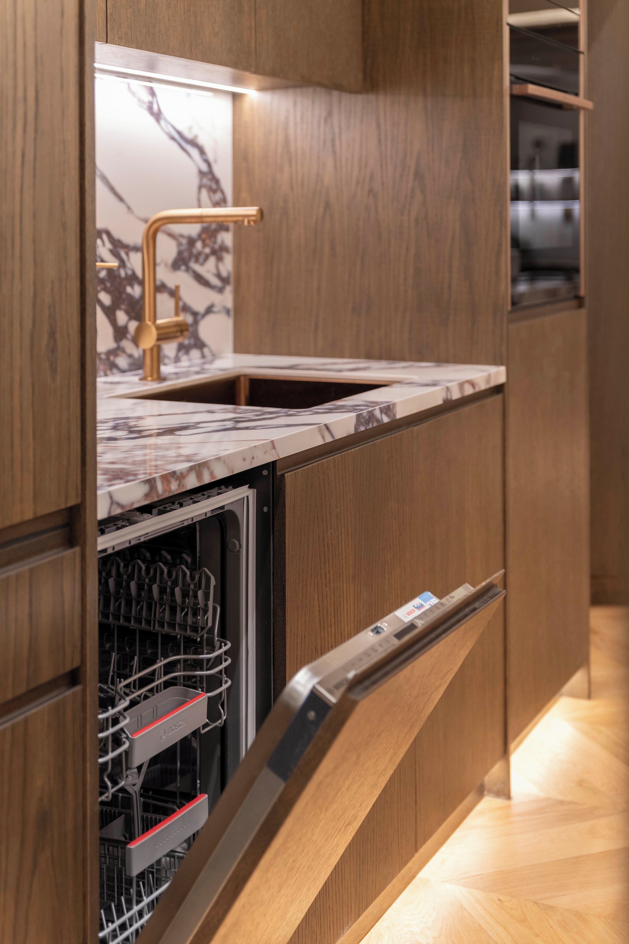A modern kitchen with a built-in dishwasher and a stainless steel sink.