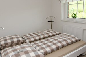 A bed with checkered bedding and a bedside table. - Holiday home in Jork with swimming pool (Jork)