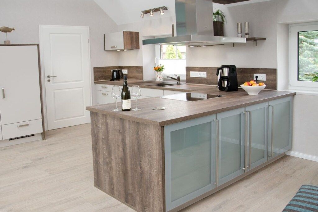 A modern kitchen with a central island, built-in appliances, and a view of the outdoors.
