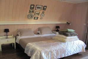 Quarto com cama, mesas de cabeceira e luminárias fixadas na parede.