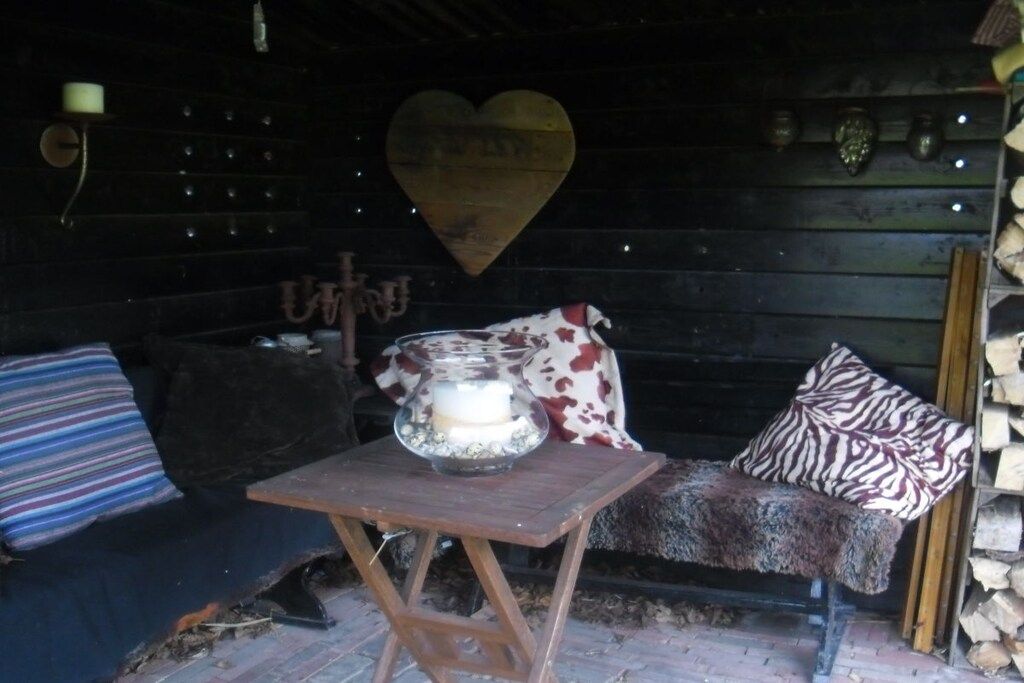 L’intérieur d’un chalet rustique, avec un banc en bois, une table sur laquelle est posée une bougie, et un décor en forme de cœur accroché au mur.