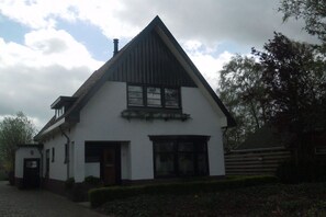 Ein traditionelles Haus mit einem steilen Satteldach, einem Hauseingang und einer kleinen Veranda.