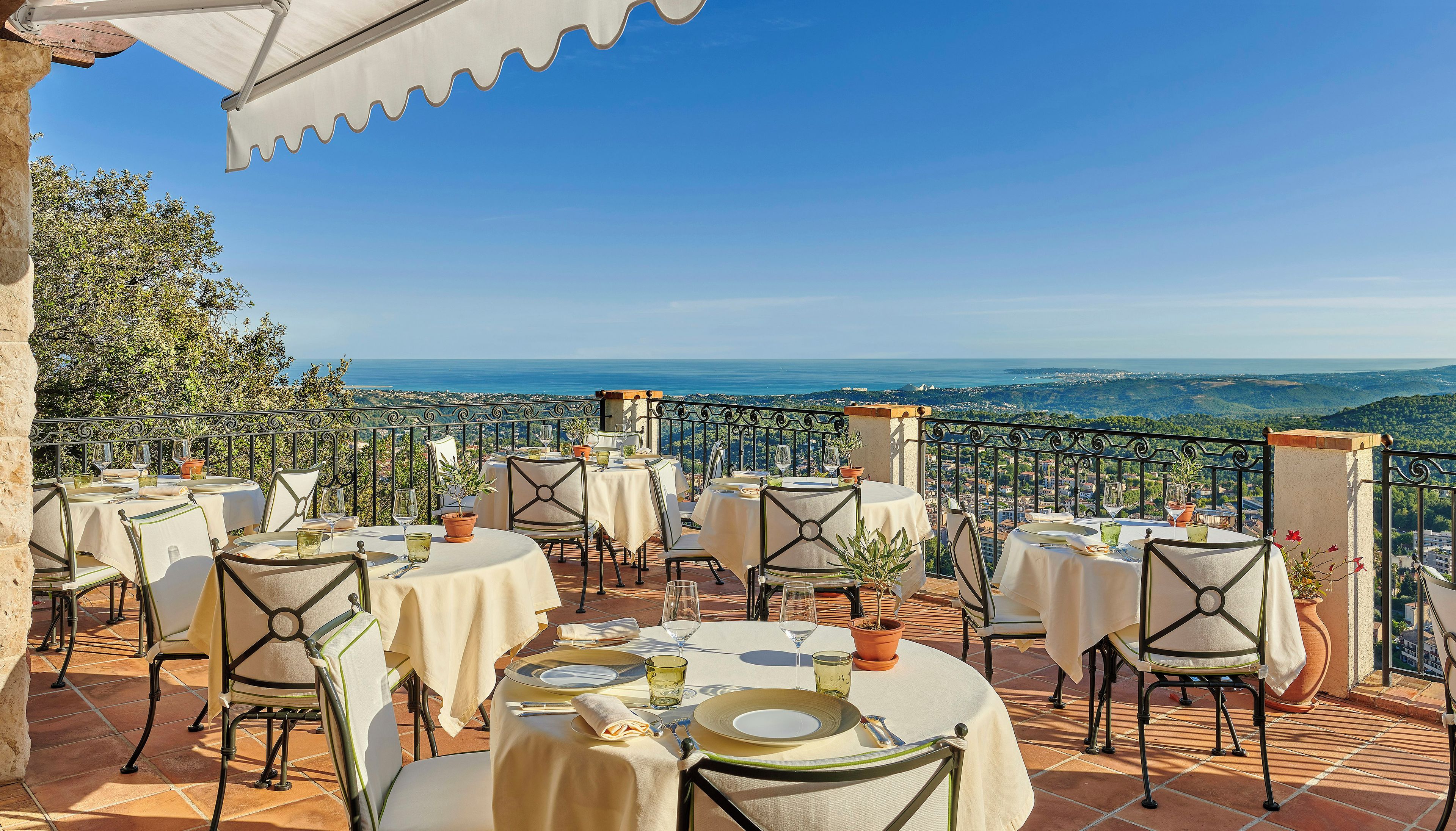 Un espace extérieur aménagé pour les repas, avec des tables pour deux personnes, offrant une vue sur un paysage pittoresque.