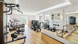 A gym with various exercise equipment, a bench, and a mirror. - Chateau Saint-martin & Spa (Vence)