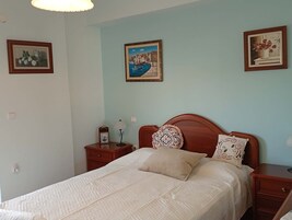 A bedroom with a bed, two nightstands, a lamp, and three framed pictures on the wall.