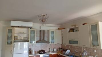 A kitchen with a refrigerator, oven, sink, and cabinets.