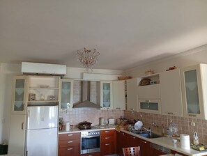 A kitchen with a refrigerator, oven, sink, and cabinets.