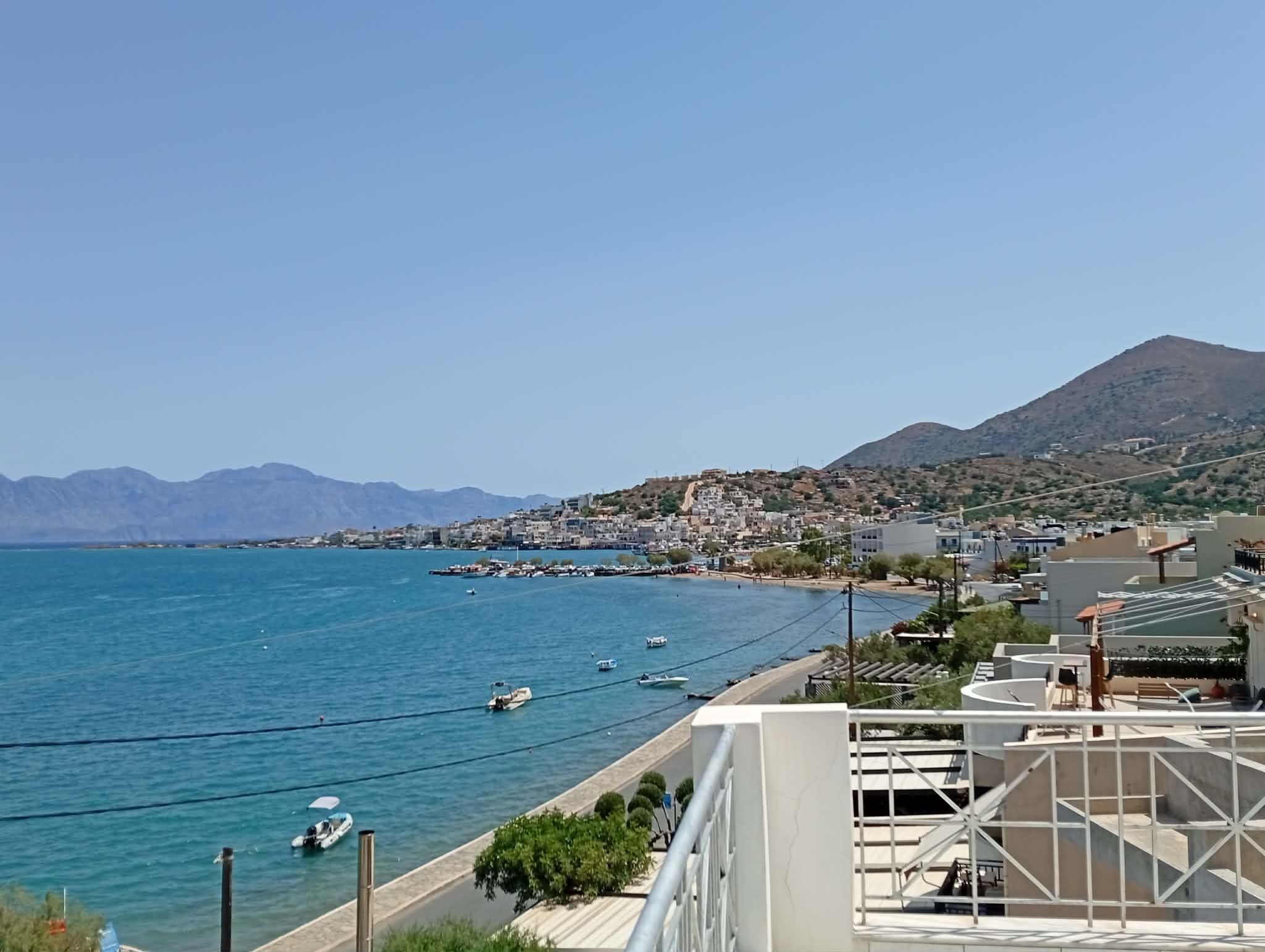 Un pueblo costero con vista despejada al mar, barcos y una montaña en la distancia.