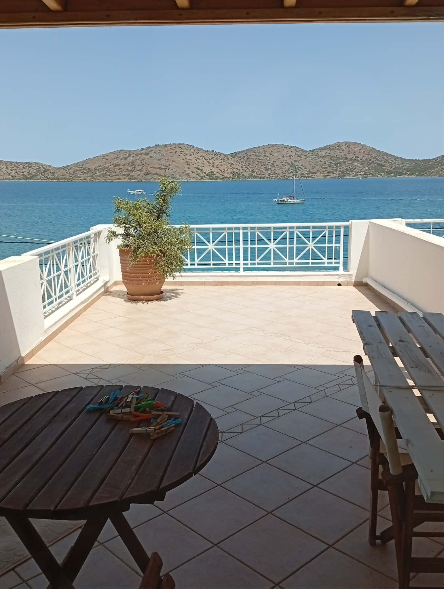 Una terraza con vistas al mar, una planta en maceta y una mesa con sillas.