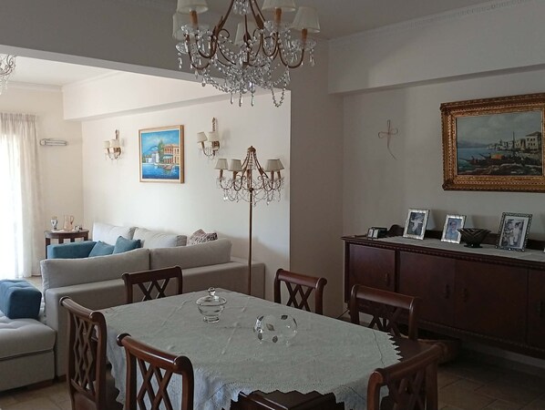A dining area with a table set for four, a chandelier, and a painting above the table.