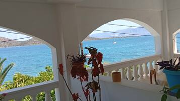 A balcony with a view of a calm sea and distant mountains.