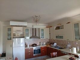 A kitchen with a refrigerator, oven, and a chandelier.