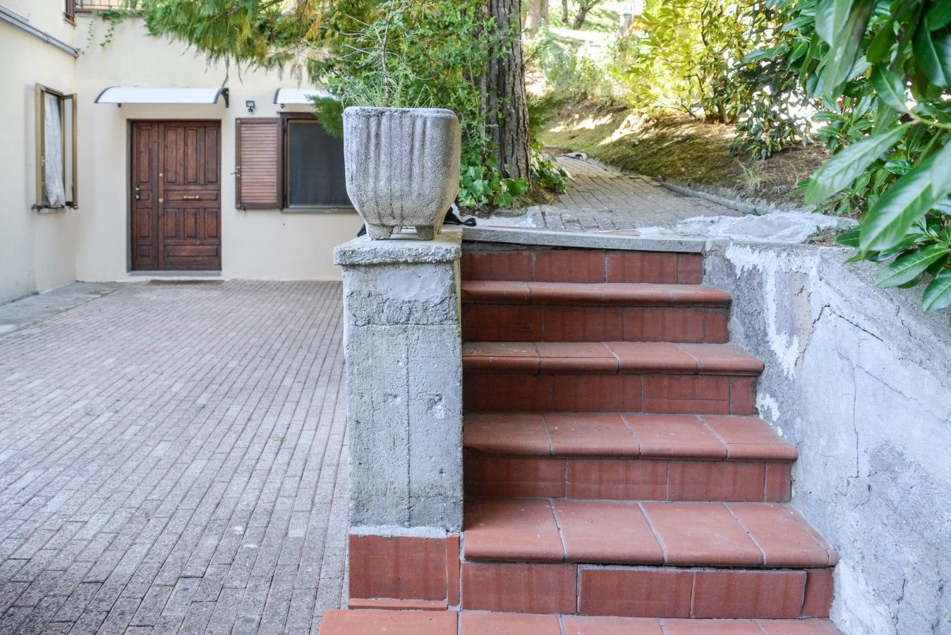 Degraus de pedra conduzem a uma entrada de edifício, com um vaso de pedra grande no primeiro degrau.