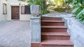 Degraus de pedra conduzem a uma entrada de edifício, com um vaso de pedra grande no primeiro degrau.