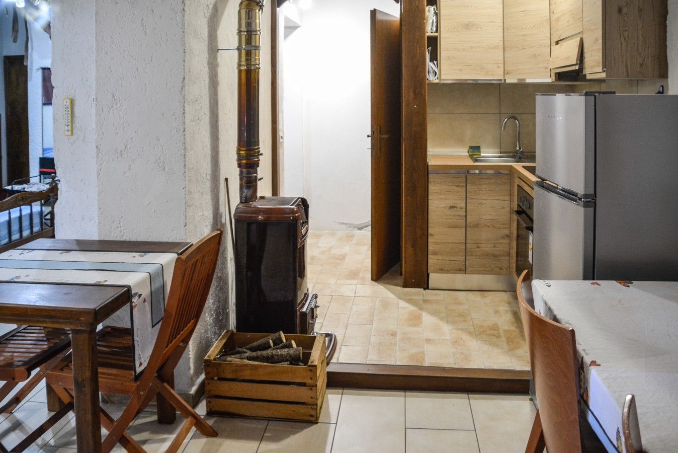 A compact kitchen with wooden cabinets, a stainless steel refrigerator, and a dining area with a table and chairs.