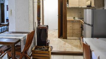 A compact kitchen with wooden cabinets, a stainless steel refrigerator, and a dining area with a table and chairs.
