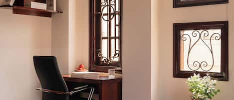 A room with a desk, chair, and a potted plant.
