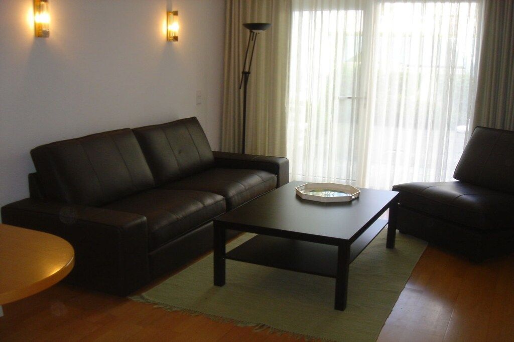 Ein Wohnzimmer mit einem dunkelbraunen Ledersofa, einem Couchtisch und einer Lampe.