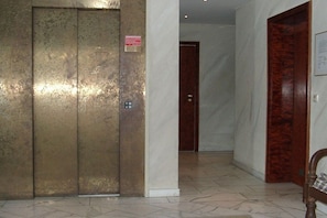 An elevator with a metallic finish, a wooden door, and a tiled floor. - House Seaside Apt. 01 (Norderney)