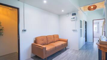 A modern interior with a sofa, a wooden reception desk, and a hallway leading to a door.