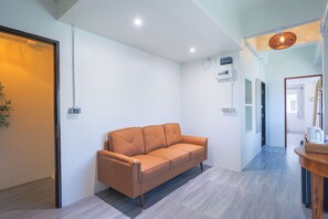 Un interior moderno con un sofá, un mostrador de recepción de madera y un pasillo que conduce a una puerta.