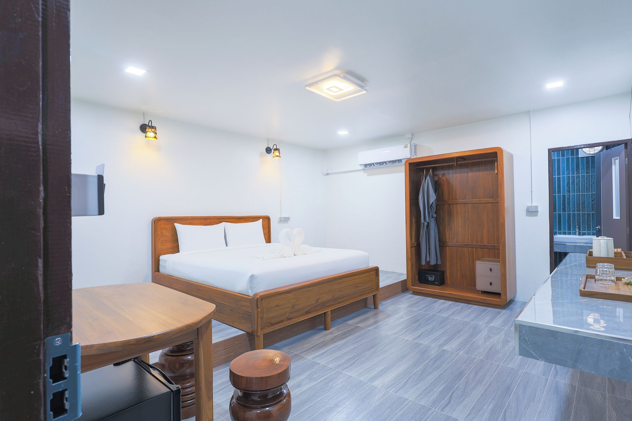 A hotel room with a bed, bedside table, and a wooden wardrobe.