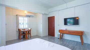 A hotel room with a bed, a desk, a chair, a TV, and a wardrobe.