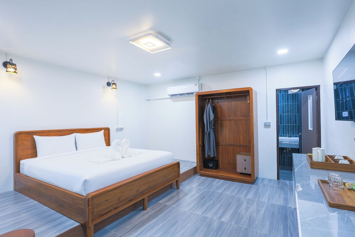 Un dormitorio moderno con una cama de madera, un vestidor y un baño con cabina de ducha de vidrio.