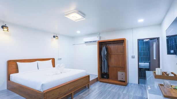 Un dormitorio moderno con una cama de madera, un vestidor y un baño con cabina de ducha de vidrio.